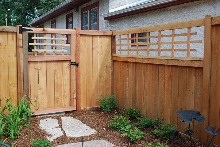 New cedar privacy fence with a matching gate and lattice top in a residential backyard, shown as a style example of cedar fencing