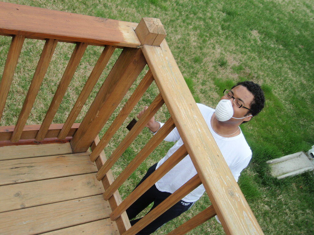 Fresh stain being applied to cedar wood, with the rich stained section contrasting against the unstained wood, shown as a style example of the staining process
